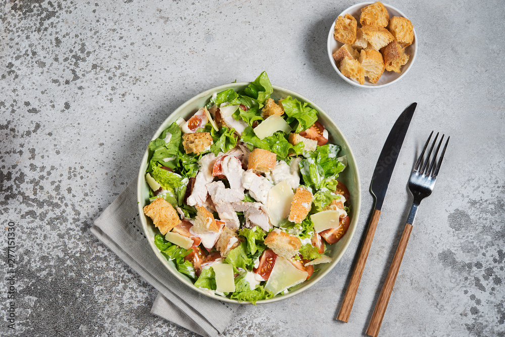 Caesar salad with chicken, Parmesan and wheat croutons on a vintage grey background. Light diet dinner. Caesar salad with chicken, Parmesan and wheat croutons on a vintage grey background. Light diet dinner.