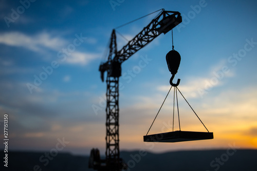 Abstract Industrial background with construction crane silhouette over amazing sunset sky. Tower crane against the evening sky. Industrial skyline photo