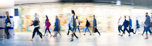Beautiful motion blur of walking people in train station. Early morning rush hours, busy modern life concept. Ideal for websites and magazines layouts
