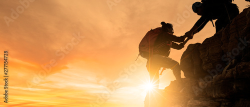 Group of Asia hiking help each other silhouette in mountains with sunlight.