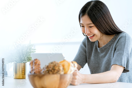 casual beautiful asian woman enjoy weekend morning withn tea and tablet white room interior background