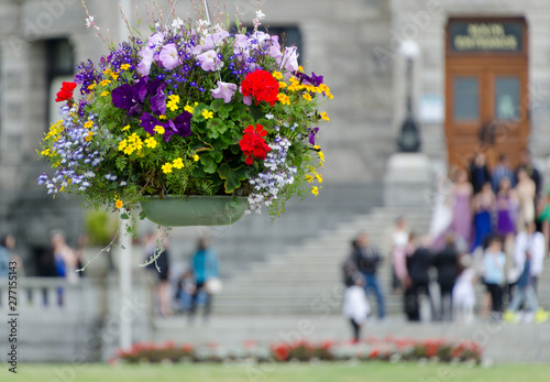 Flowers basket in front of tourists crowd gathered on steps of Parliament building in Victoria
