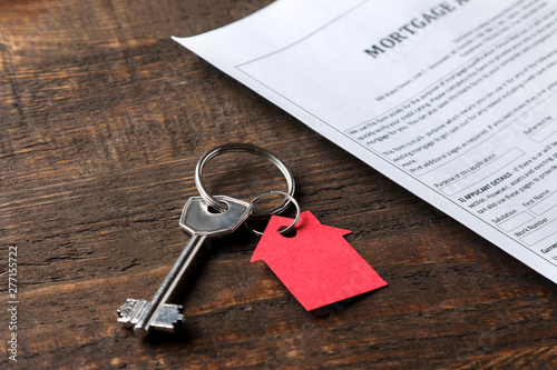 mortgage application. Key with red keychain house and blank on a brown wooden table. concept of buying a home.