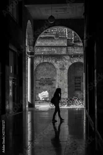 Silhouette of the woman on the phone walking under this beautiful marble arc in the center of Brescia, Italy. © Zuzana