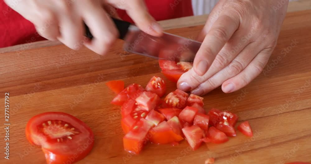 Chef cutting red tomato using sharp knife, close up, handheld footage Chef cutting red tomato using sharp knife, close up, handheld footage