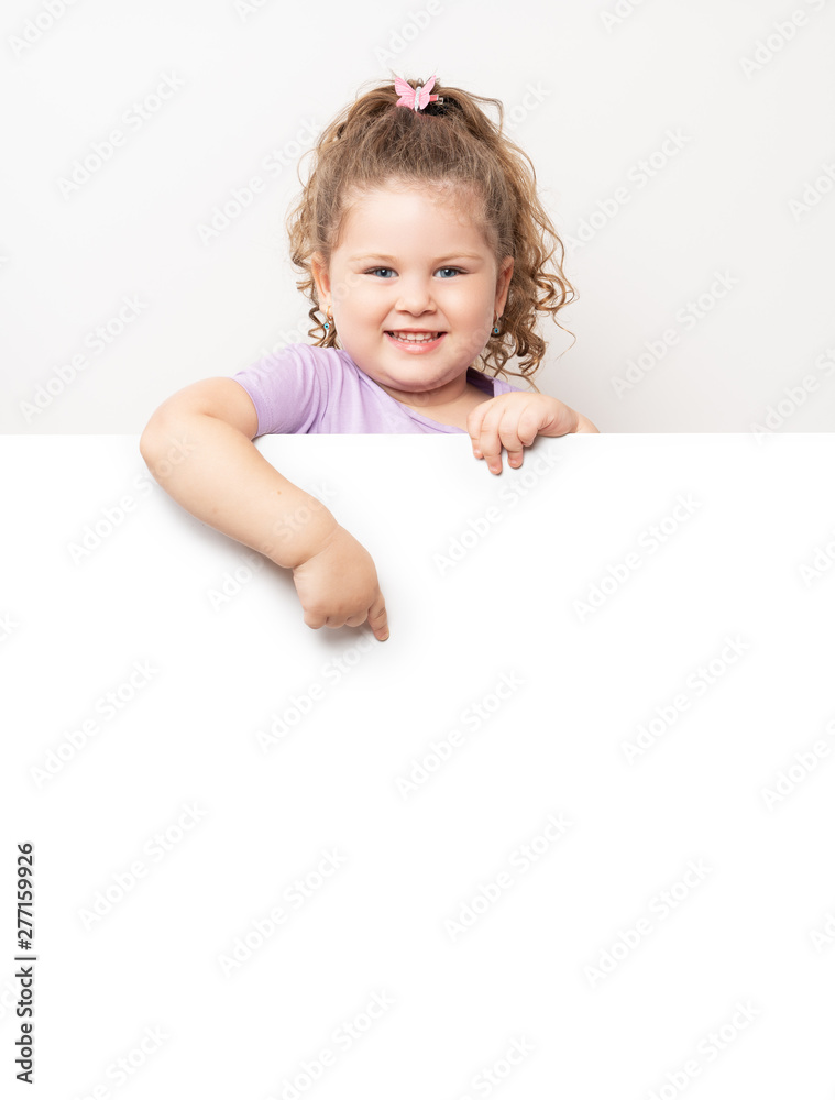 Smiling blue eyed little girl peeking behind a white board