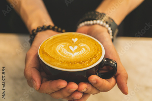 Female hands holding a cup of hot late'