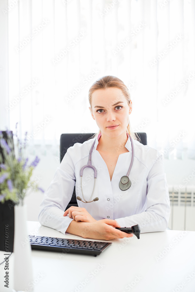 Young smiling doctor sitting at the desk on a black chair with her arms crossed Young smiling doctor sitting at the desk on a black chair with her arms crossed