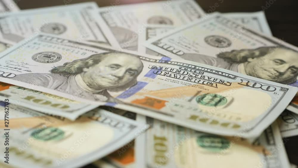 One hundred dollar bills chaotically fall on the table One hundred dollar bills chaotically fall on the table