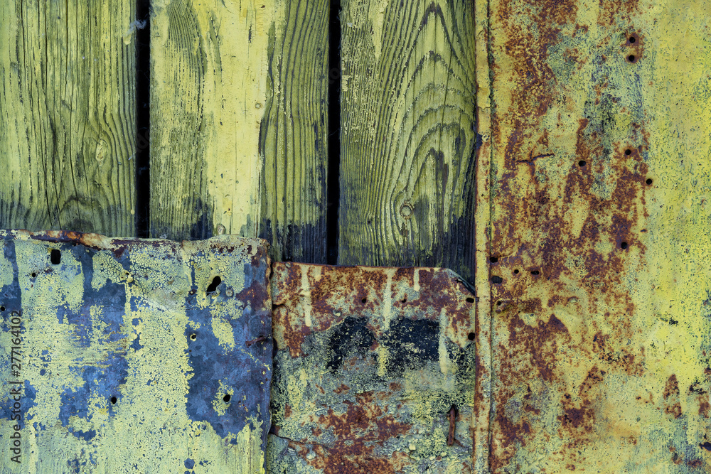 old faded wooden planks and metal patch for them. Metal patch on the wooden door. Green peeling wooden background