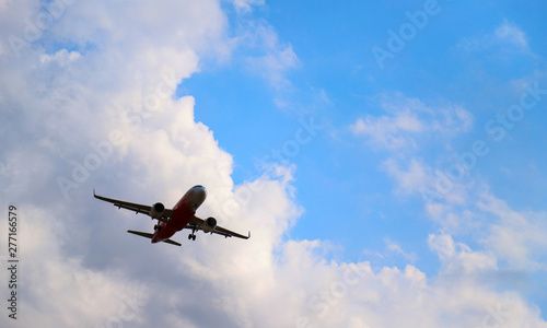An airplane is flying in sunny day with cloudy blue sky background. 