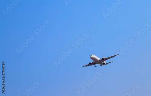 An airplane is flying in sunny day with blue sky background. 