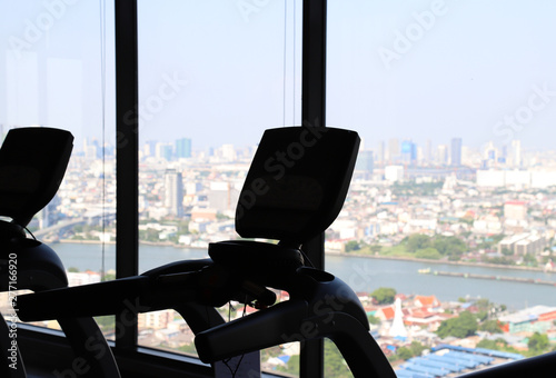 Silhouette image of equipment in the skyscraper fitness center with city background. 
