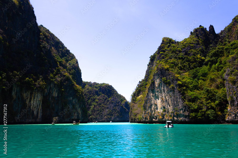 Beach in Krabi province. Vie of Maya Bay, Phi Phi island. Hong islands lagoon. Gray green stone rock on the background of crystal clear water in the sea. Beach in Krabi province. Vie of Maya Bay, Phi Phi island. Hong islands lagoon. Gray green stone rock on the background of crystal clear water in the sea.