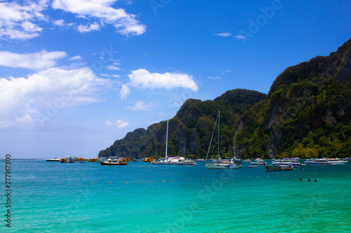 Port with sailboats in a lagoon with clear blue sea water on a background of wild rocks in Thailand. Turquoise sea  blue sky and boats near the rocks on the Islands.