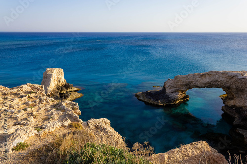 Beautiful view of the blue Mediterranean sea and the rock arch on a Sunny day from Cape Greco in Cyprus. Stone landscape of Ayia NAPA. Yellow rocks in the sea.
