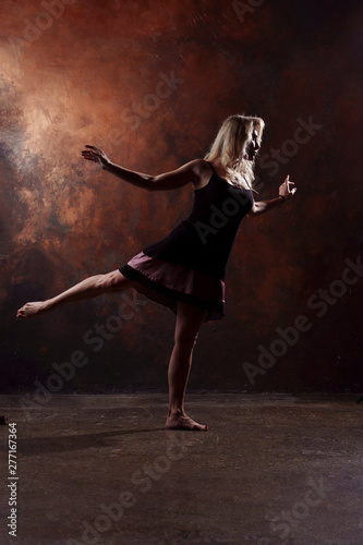 Fototapeta Naklejka Na Ścianę i Meble -  Full-length photo of dancing blonde woman looking in side in short black dress on brown background