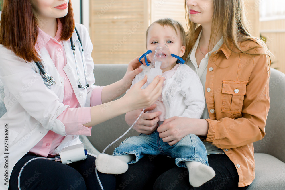 woman doctor hold a mask vapor inhaler for little baby girl . infant baby receives a nebulizer treatment through the facial mask woman doctor hold a mask vapor inhaler for little baby girl . infant baby receives a nebulizer treatment through the facial mask