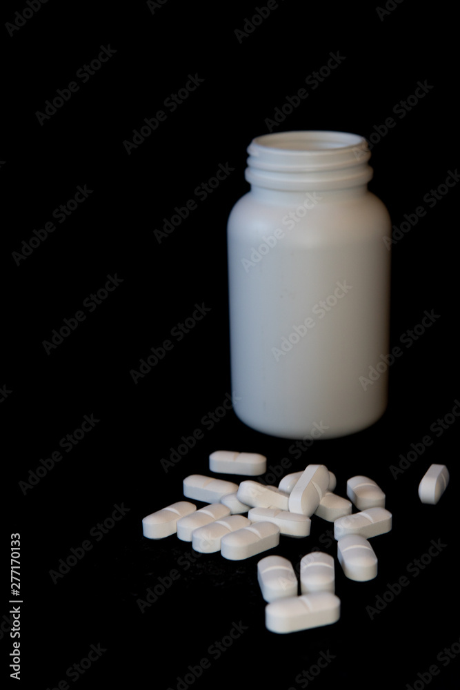 multiple white pills infront of a white pill botle, separated background, black multiple white pills infront of a white pill botle, separated background, black