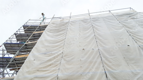 Large scaffolding on a building with an empty gray tarpaulin © OceanProd