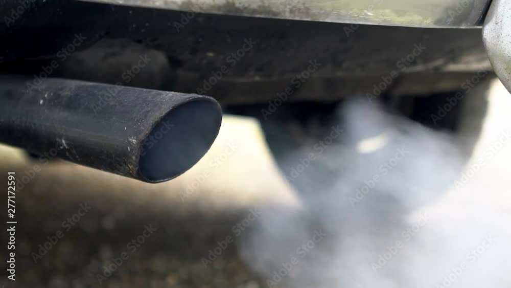 Close-up combustion fumes coming out of car exhaust pipe which strongly of white smoke. Poisonous carbon monoxide from vehicle on road, air pollution concept. Fume emissions in the traffic-Dan Close-up combustion fumes coming out of car exhaust pipe which strongly of white smoke. Poisonous carbon monoxide from vehicle on road, air pollution concept. Fume emissions in the traffic-Dan