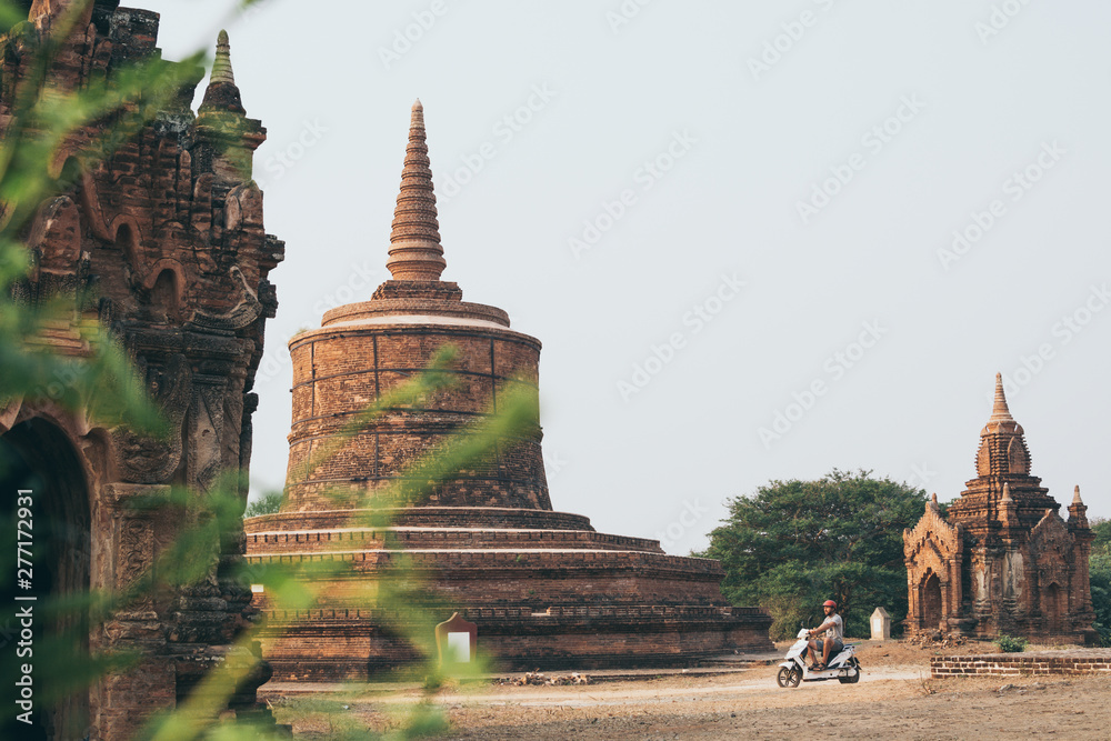 Man riding electric scooter towards temples and pagodas of ancient Bagan in Myanmar