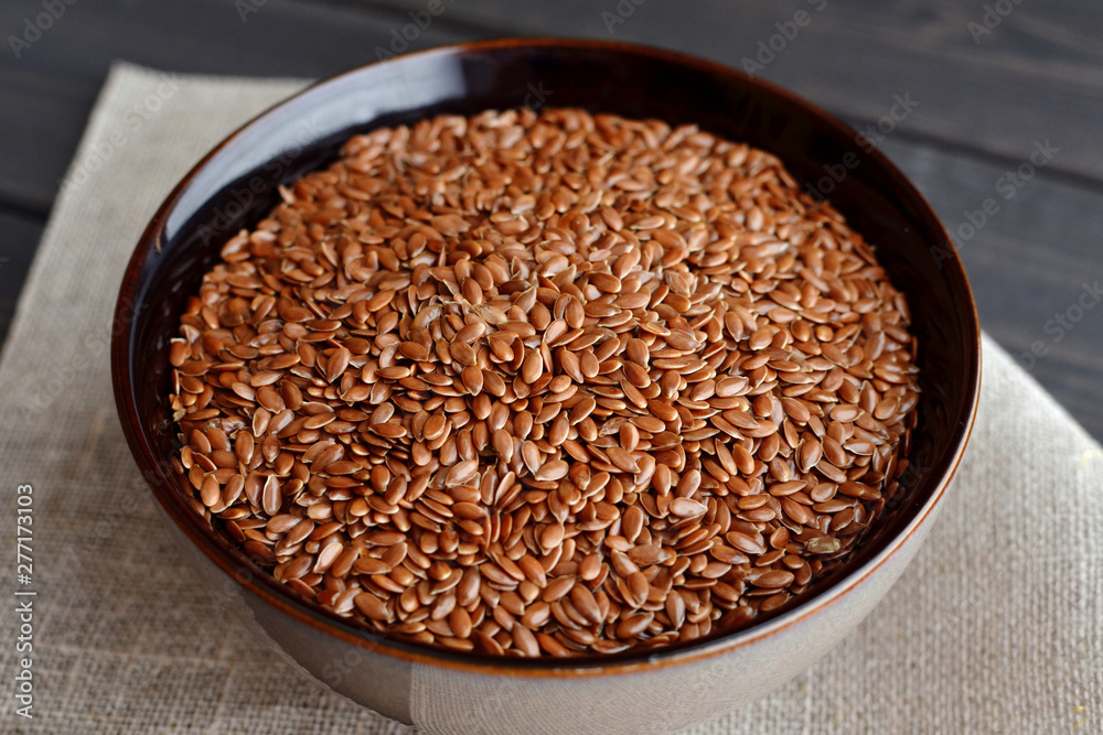 flax seeds in bowl with linen fabric on wooden background flax seeds in bowl with linen fabric on wooden background