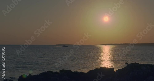 Boat is driving in the backlight over the sea before sunset