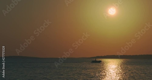 Boat is driving in the backlight over the sea before sunset