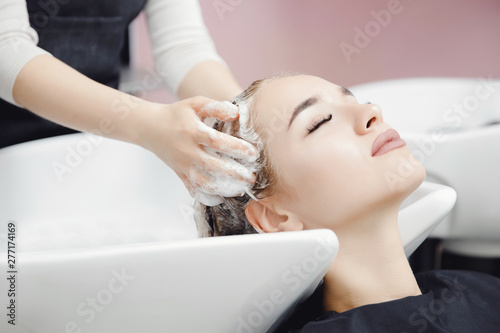 Concept head massage. Beautiful blond woman getting hair wash in beauty salon