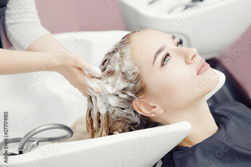 Beautiful blond woman getting hair wash in beauty salon. Concept head massage