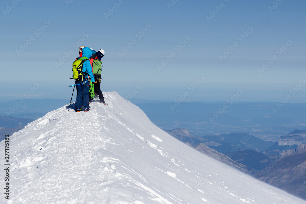 A group of mountaineers climbs to the top of a snow-capped mountain