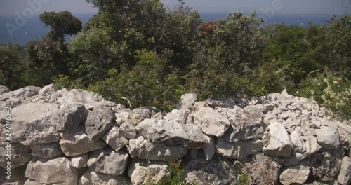 Pan over a dry stone wall with macchia in the background at the island losinj 