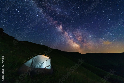 Fototapeta Naklejka Na Ścianę i Meble -  Fantastic starry night with galaxy Milky Way with a tourist and a tent on the mountain range in the Ukrainian Carpathians