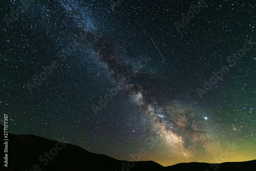 Fantastic starry night with galaxy Milky Way with a tourist and a tent on the mountain range in the Ukrainian Carpathians