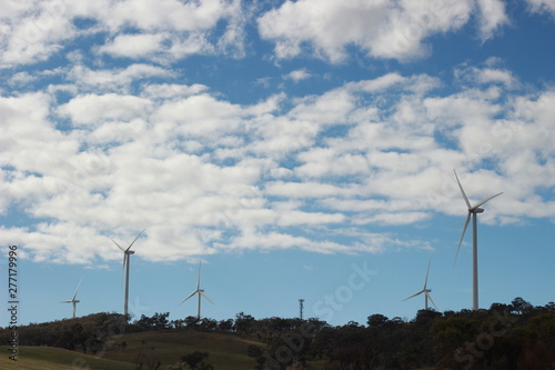 panoramic views of multiple windmills at a modern wind farm built on a green hill on a sunny blue sky cloudy day, Rurul Victoria, near Melbourne