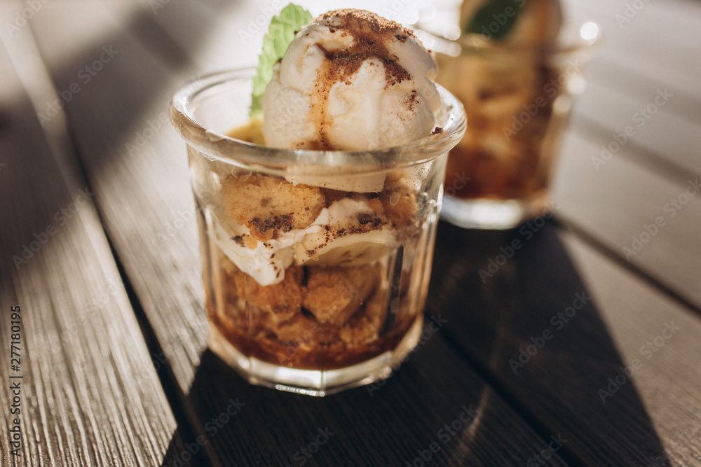 Ice ceam with chocolate and mint in glass cup on wooden table in street cafe. Food, dessert concept Ice ceam with chocolate and mint in glass cup on wooden table in street cafe. Food, dessert concept