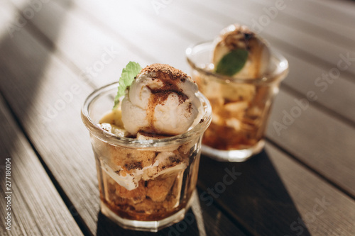 Ice ceam with chocolate and mint in glass cup on wooden table in street cafe. Food, dessert concept