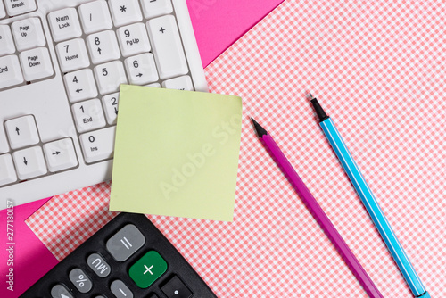 Note paper stick to computer keyboard near colored gift wrap sheet on table