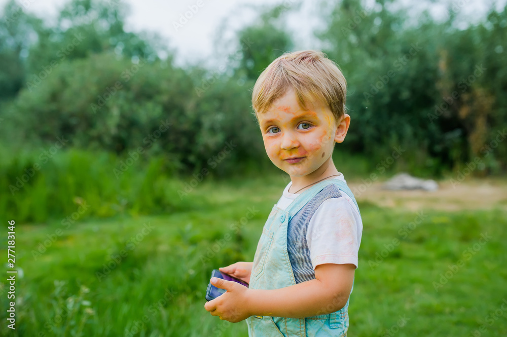 Little child boy painted on face paint. Portrait of dirty little boy with gadget outdoors Little child boy painted on face paint. Portrait of dirty little boy with gadget outdoors