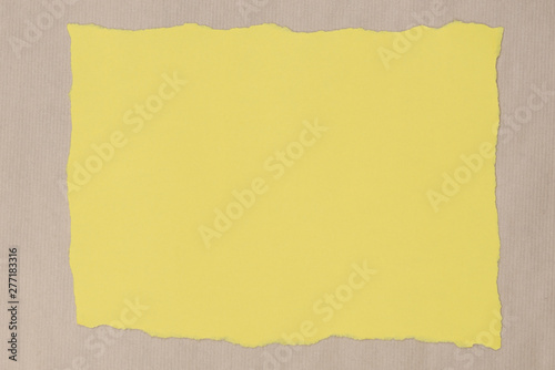 yellow piece of torn paper on recycled paper background texture
