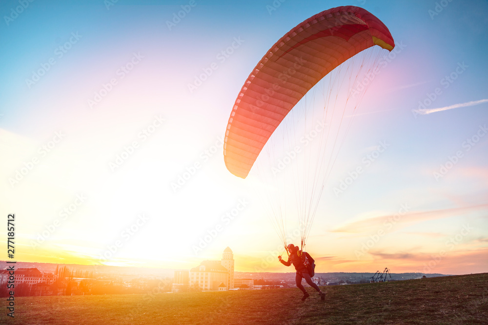 Paraglider getoff ground with wind against sunset - obrazy, fototapety, plakaty 