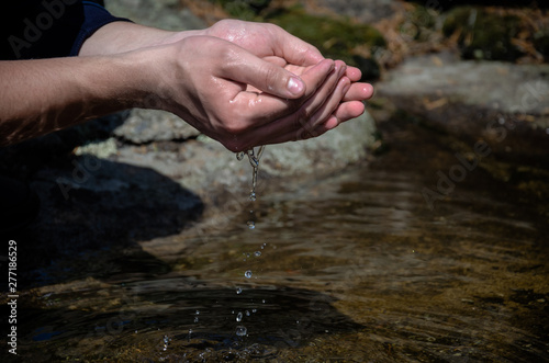 Beautiful hands on a wild brook. Stream of clean water pouring into hands