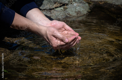 Beautiful hands on a wild brook. Stream of clean water pouring into hands