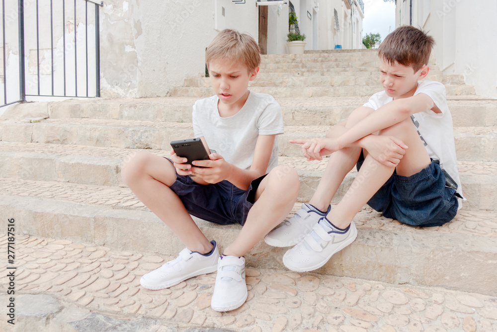 Children talking and using mobile phone outdoors Children talking and using mobile phone outdoors