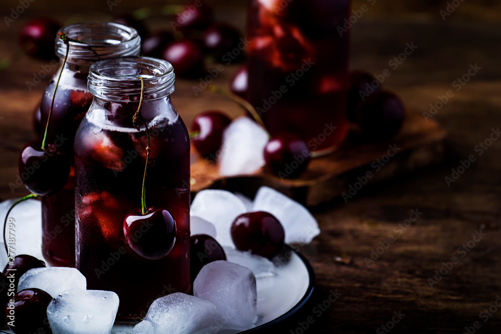 Cherry drink, cold juice with ice in bottles on vintage wooden table, summer fruit cocktail Cherry drink, cold juice with ice in bottles on vintage wooden table, summer fruit cocktail