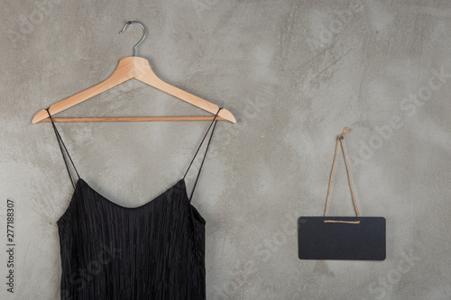Fashion and shopping concept - blank blackboard and beautiful little black dress on a hanger photo