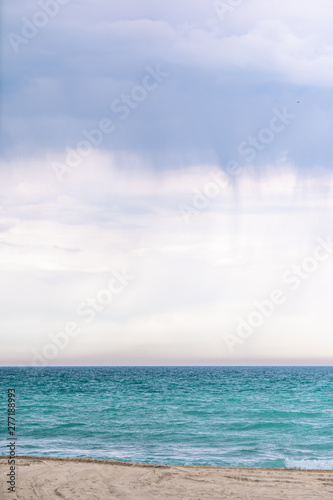 Tropical island beach and sea at cloudy weather. Rain are happening at sea