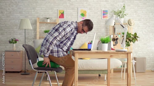 man sits on a round orthopedic pillow and starts working on a laptop