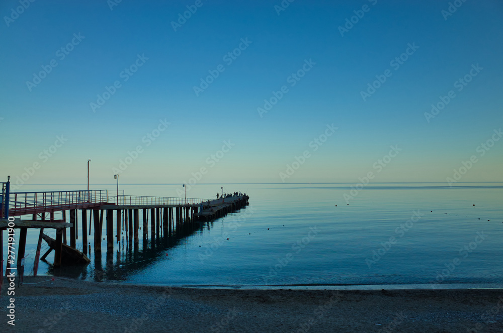 Evening in Sudak, the Republic of Crimea. Fishermen on the pier. Black Sea Coast